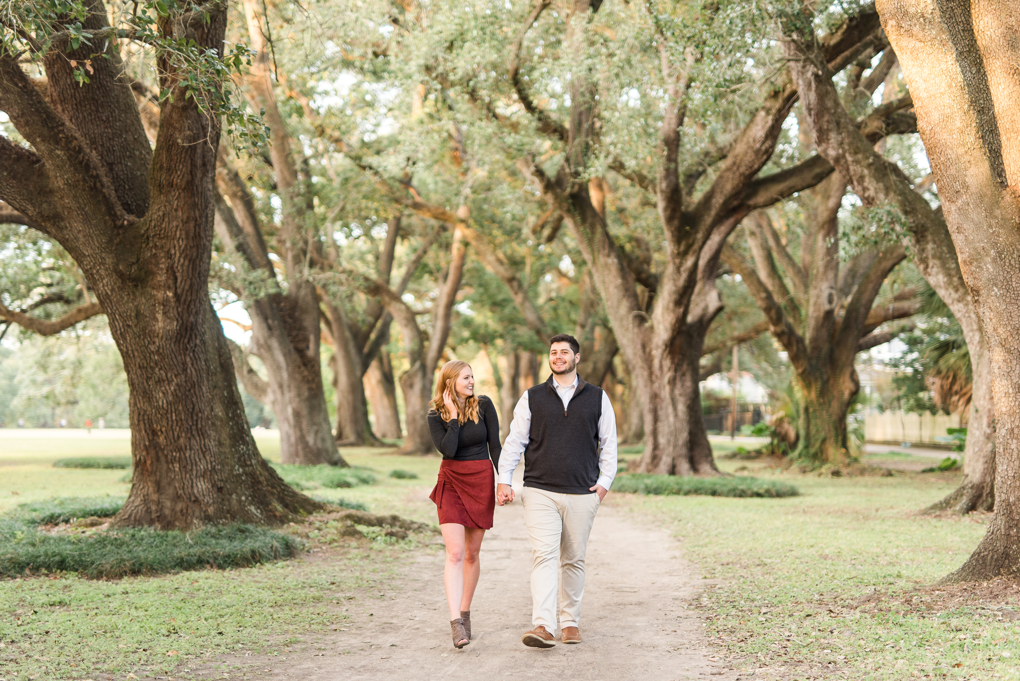 engaged couple strolls through oak trees in audubon park